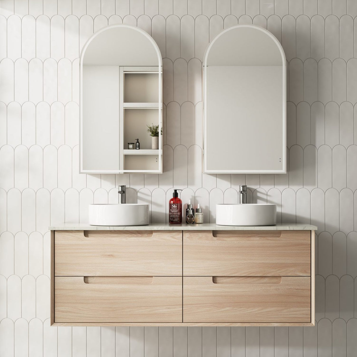 Bathroom vanity with double sink, mirrors, and decorative items against a tiled wall.