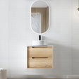 Bathroom vanity with wooden cabinet, white sink, and oval mirror on a light gray wall.