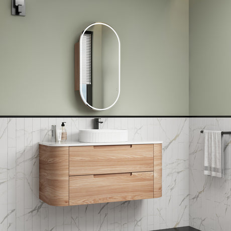 Bathroom vanity with wooden cabinet, white countertop, and mirror against a green wall.