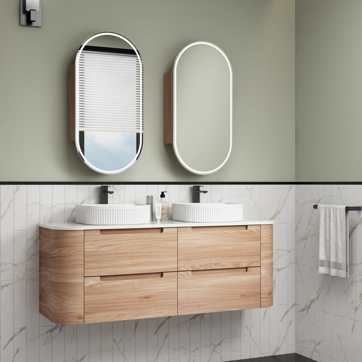 Bathroom vanity with wooden cabinets, white countertop, and two oval mirrors on a green wall.