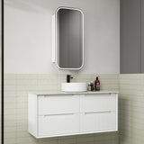 Bathroom vanity with white cabinet, round sink, and mirror above in a tiled bathroom.