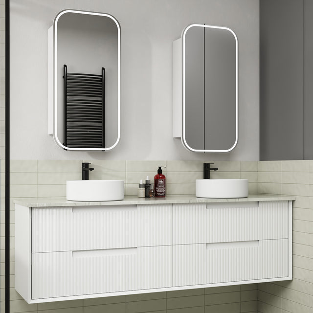 Bathroom vanity with two white sinks, mirrors, and toiletries on a tiled wall.