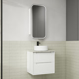 Bathroom vanity with white sink and mirror against a tiled wall.
