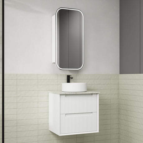 Bathroom vanity with white sink and mirror against a tiled wall.