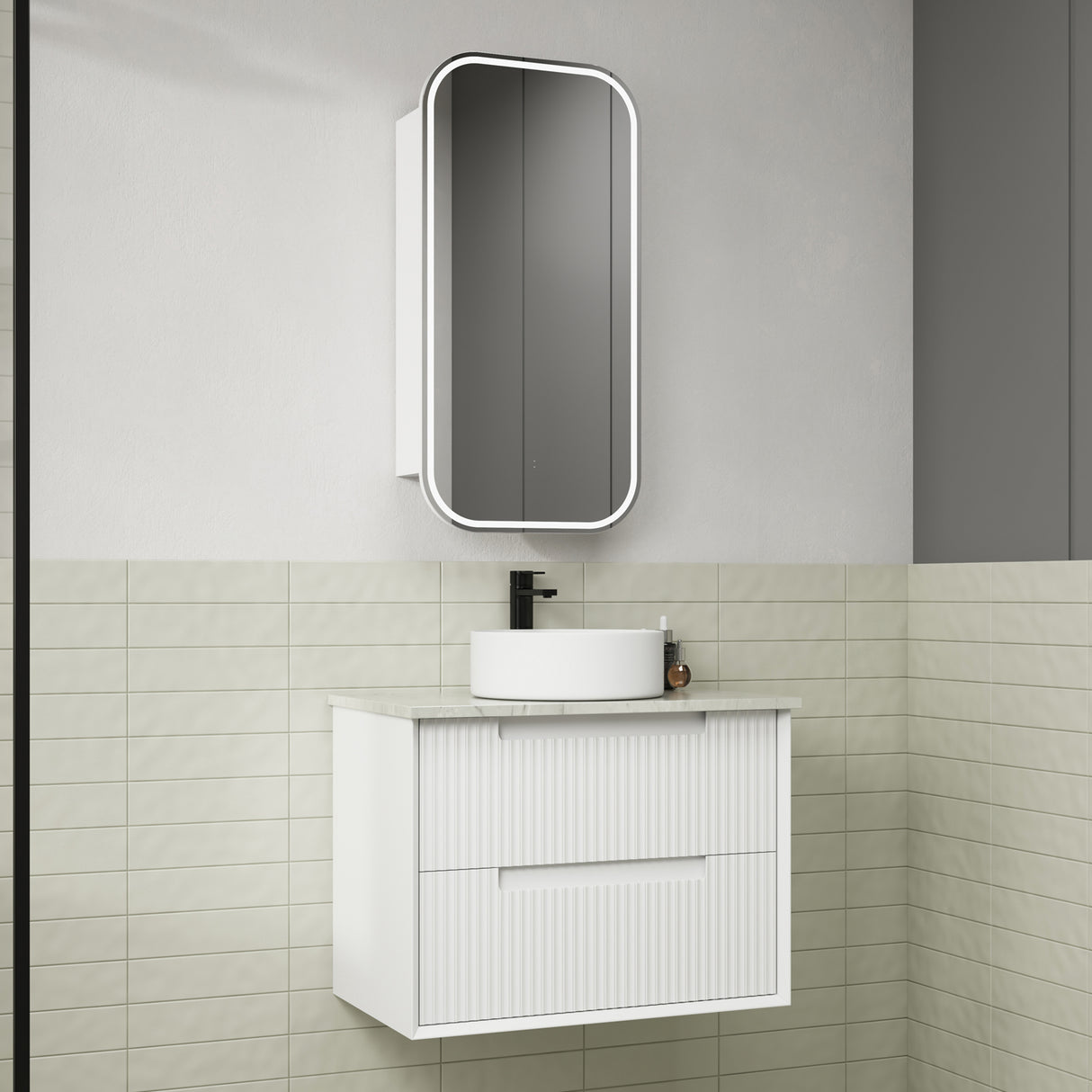Bathroom setup with a white vanity unit, sink, and mirror against a tiled wall.