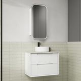 Bathroom setup with a white vanity unit, sink, and mirror against a tiled wall.