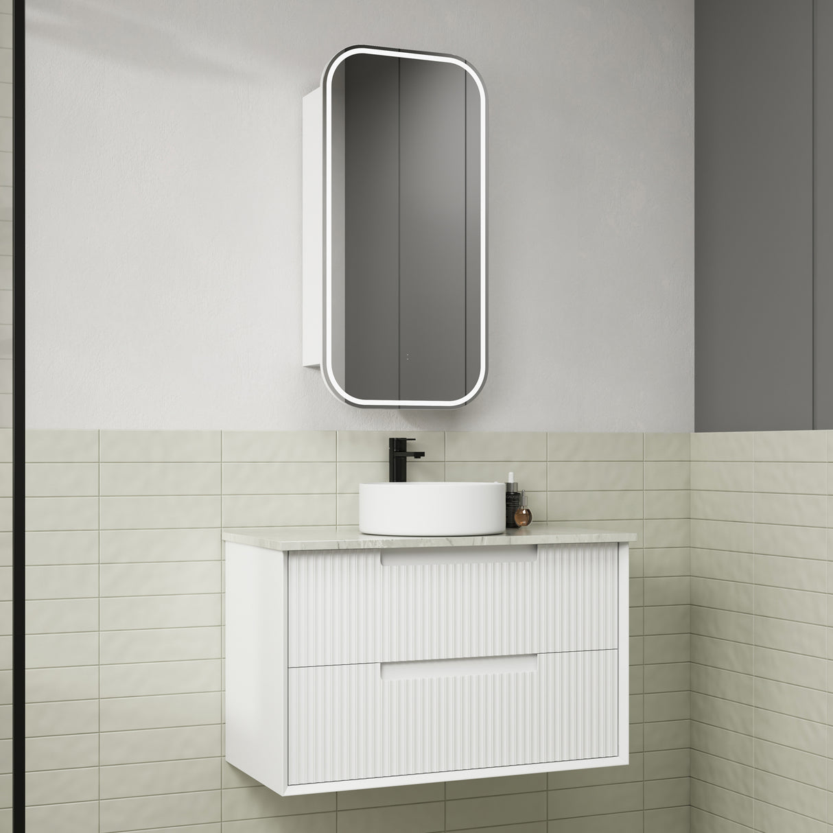 Bathroom vanity with white cabinet, round sink, and rectangular mirror on a tiled wall.