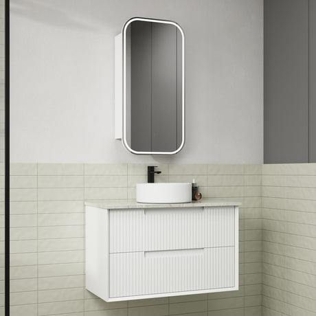 Bathroom vanity with white cabinet, round sink, and rectangular mirror on a tiled wall.