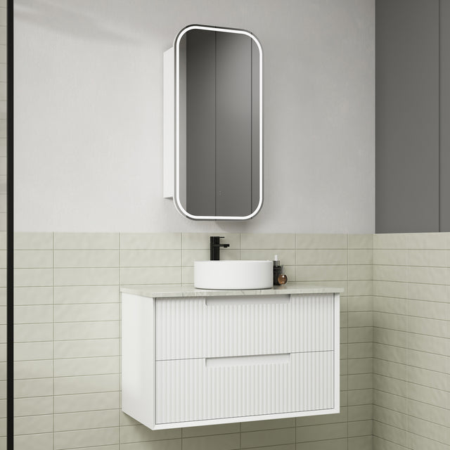 Bathroom vanity with white cabinet, round sink, and rectangular mirror on a tiled wall.