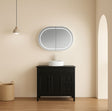 Bathroom vanity with a round mirror and light fixture on a beige wall.