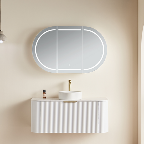 Bathroom setup with a white vanity, sink, and illuminated mirror on a beige wall.