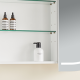 Bathroom cabinet with glass shelves containing skincare products.