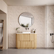 Bathroom with wooden vanity, round mirror, and tiled walls.