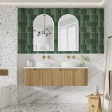 Bathroom with green tiled wall, wooden vanity, and white marble floor.