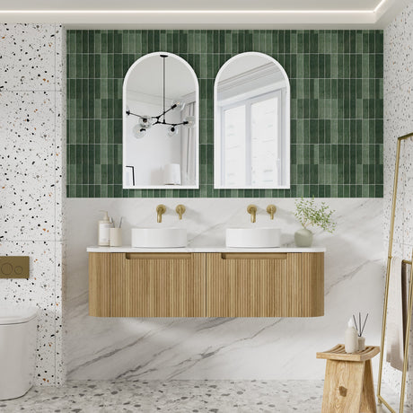 Bathroom with green tiled wall, wooden vanity, and white marble floor.