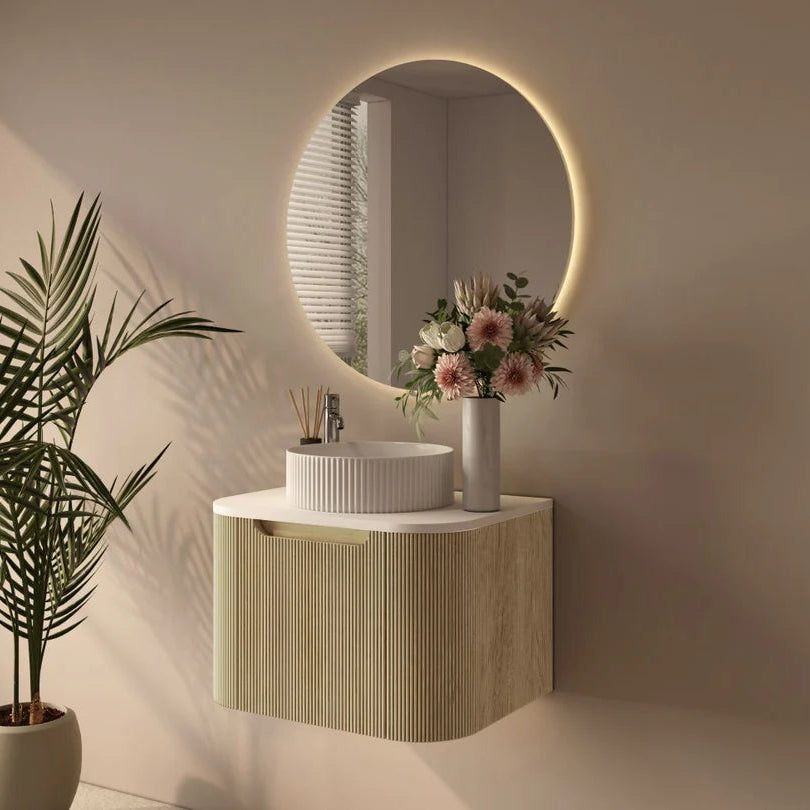 Modern bathroom with round mirror, sink, and decorative plant.