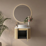 Bathroom vanity with round mirror, sink, and decorative elements on a beige wall.
