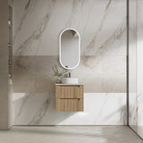 Modern bathroom with marble walls, wooden vanity, and round mirror.