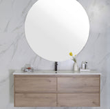Bathroom vanity with wooden cabinet, round mirror, and decorative items on a marble wall background