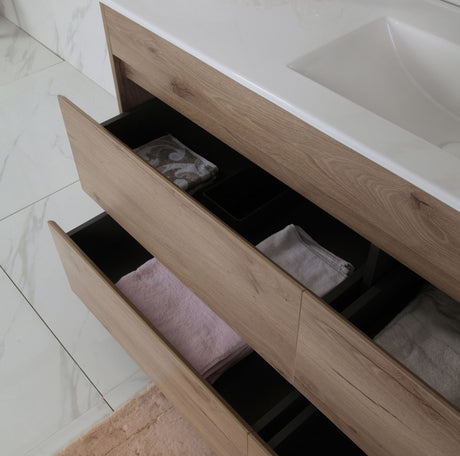 Bathroom vanity with open drawers containing towels on a tiled floor.