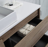 Bathroom vanity with open drawer revealing folded towels, sink, and cup on countertop.