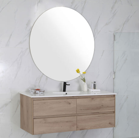 Bathroom vanity with wooden cabinet, round mirror, and marble wall.