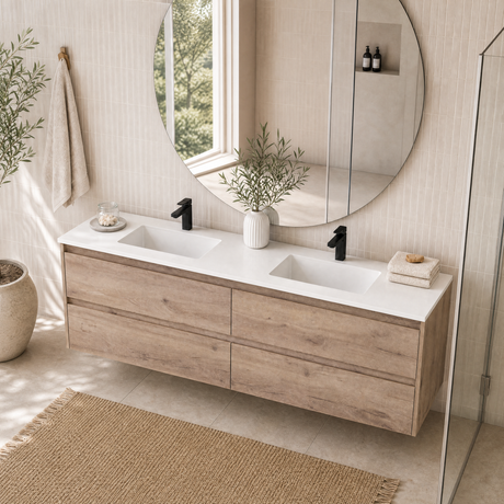 A modern floating double-sink bathroom vanity with a light oak wood finish and white countertop, shown in a bright, sunlit bathroom setting with a large round mirror and a glass shower door.