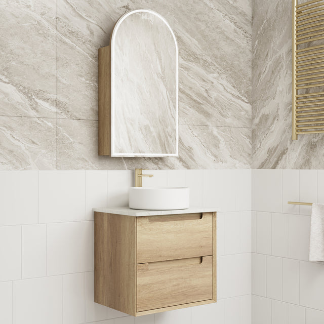Bathroom vanity with wooden cabinet, white sink, and mirror against a tiled wall.