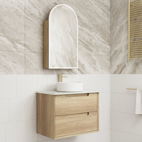 Bathroom vanity with wooden cabinet, white sink, and mirror against a tiled wall.