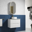 Bathroom with blue tiled wall, white vanity, and oval mirror.