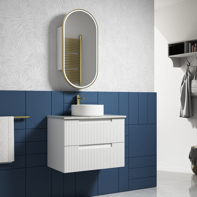 Bathroom with blue tiled wall, white vanity, and oval mirror.
