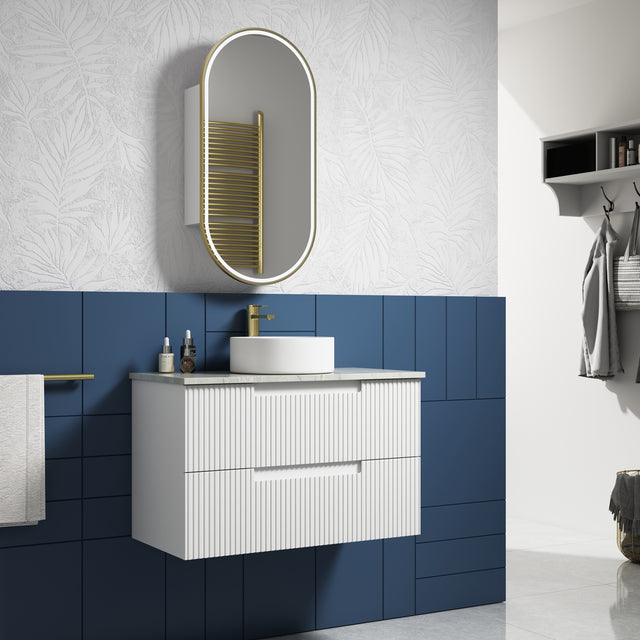 Bathroom with white vanity, blue tiled walls, and oval mirror.