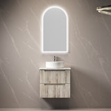 Bathroom vanity with illuminated mirror against a marble wall.