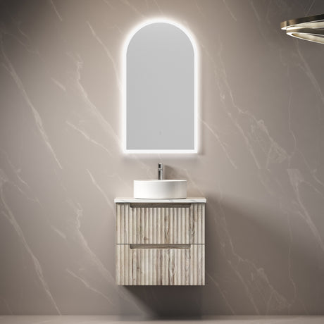 Bathroom vanity with illuminated mirror against a marble wall.