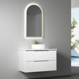 Bathroom vanity with illuminated mirror and sink against a gray wall.