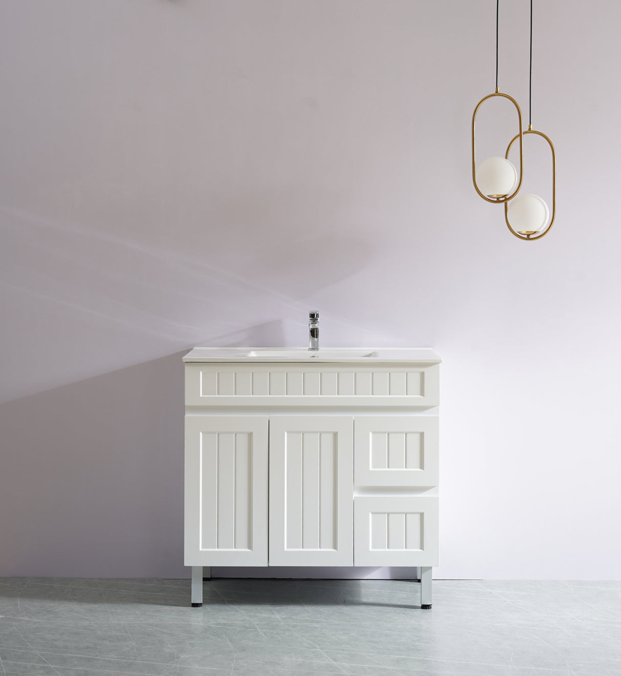 White bathroom vanity with sink against a plain wall with two gold pendant lights.