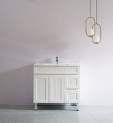 White bathroom vanity with sink against a plain wall with two gold pendant lights.