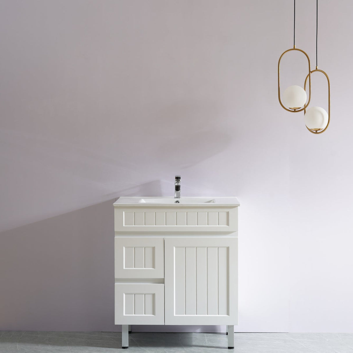 White bathroom vanity with sink against a plain wall with two gold pendant lights.