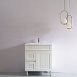 White bathroom vanity with sink against a plain wall with two gold pendant lights.