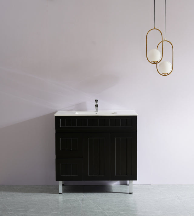 Black bathroom vanity with white countertop against a plain wall with gold pendant lights.