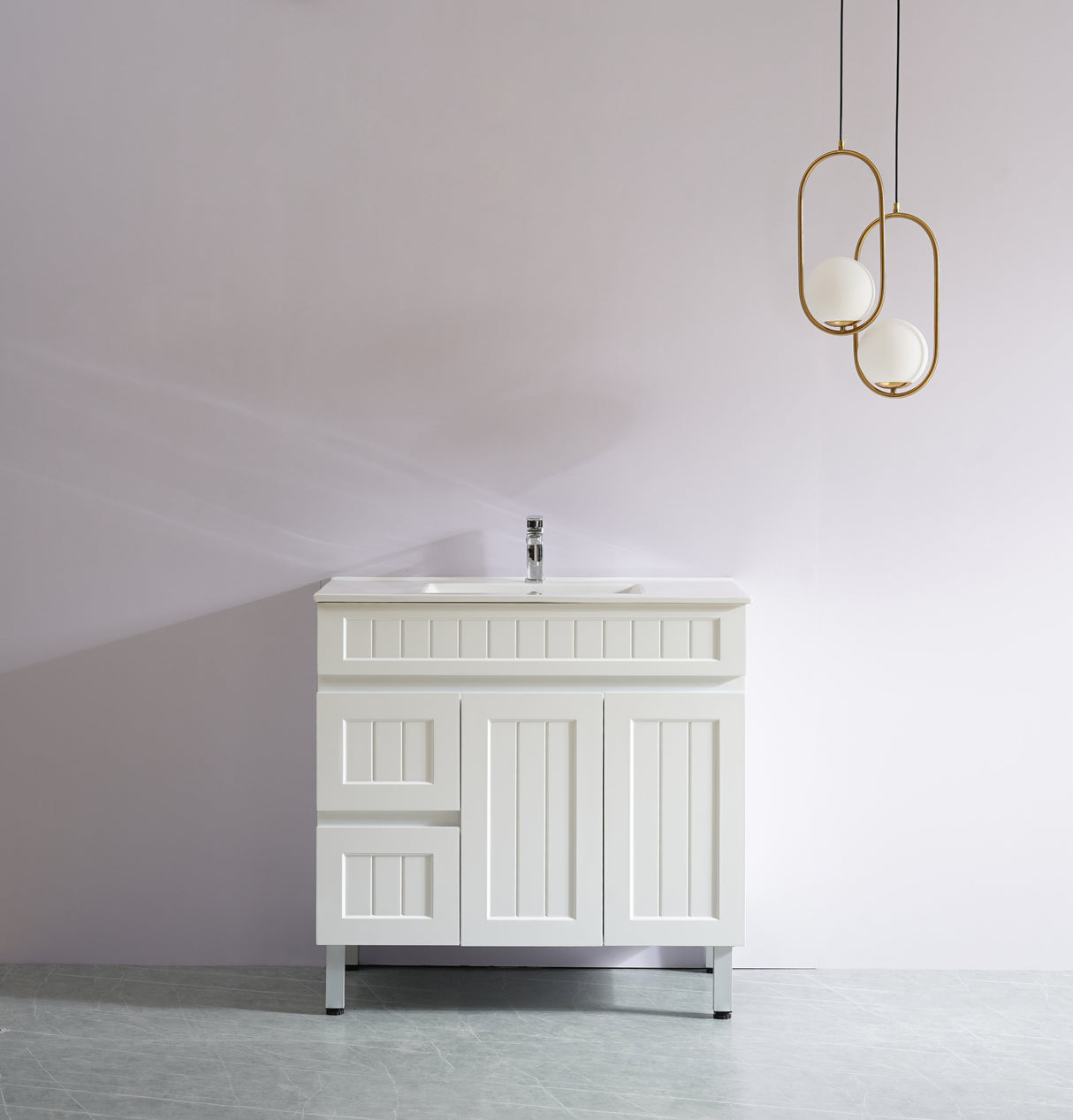 White bathroom vanity with sink against a plain wall with two gold pendant lights.