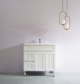 White bathroom vanity with sink against a plain wall with two gold pendant lights.