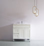 White bathroom vanity with sink against a plain wall with two gold pendant lights.