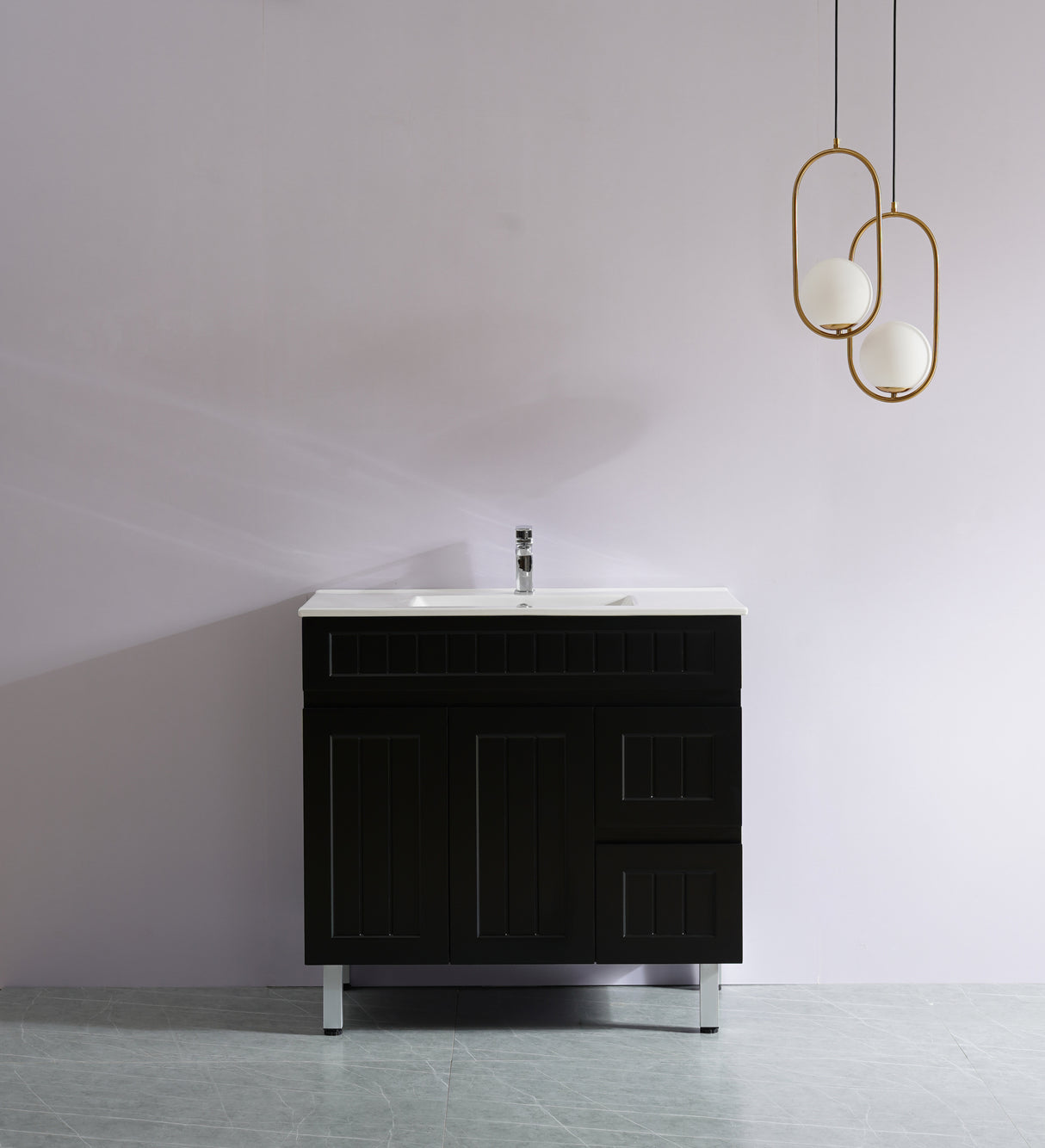 Black bathroom vanity with white sink against a gray wall with gold pendant lights.