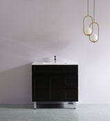 Black bathroom vanity with white sink against a gray wall with gold pendant lights.