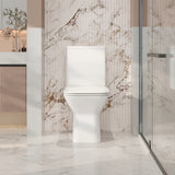 White toilet in a modern bathroom with marble walls and a glass shower door.