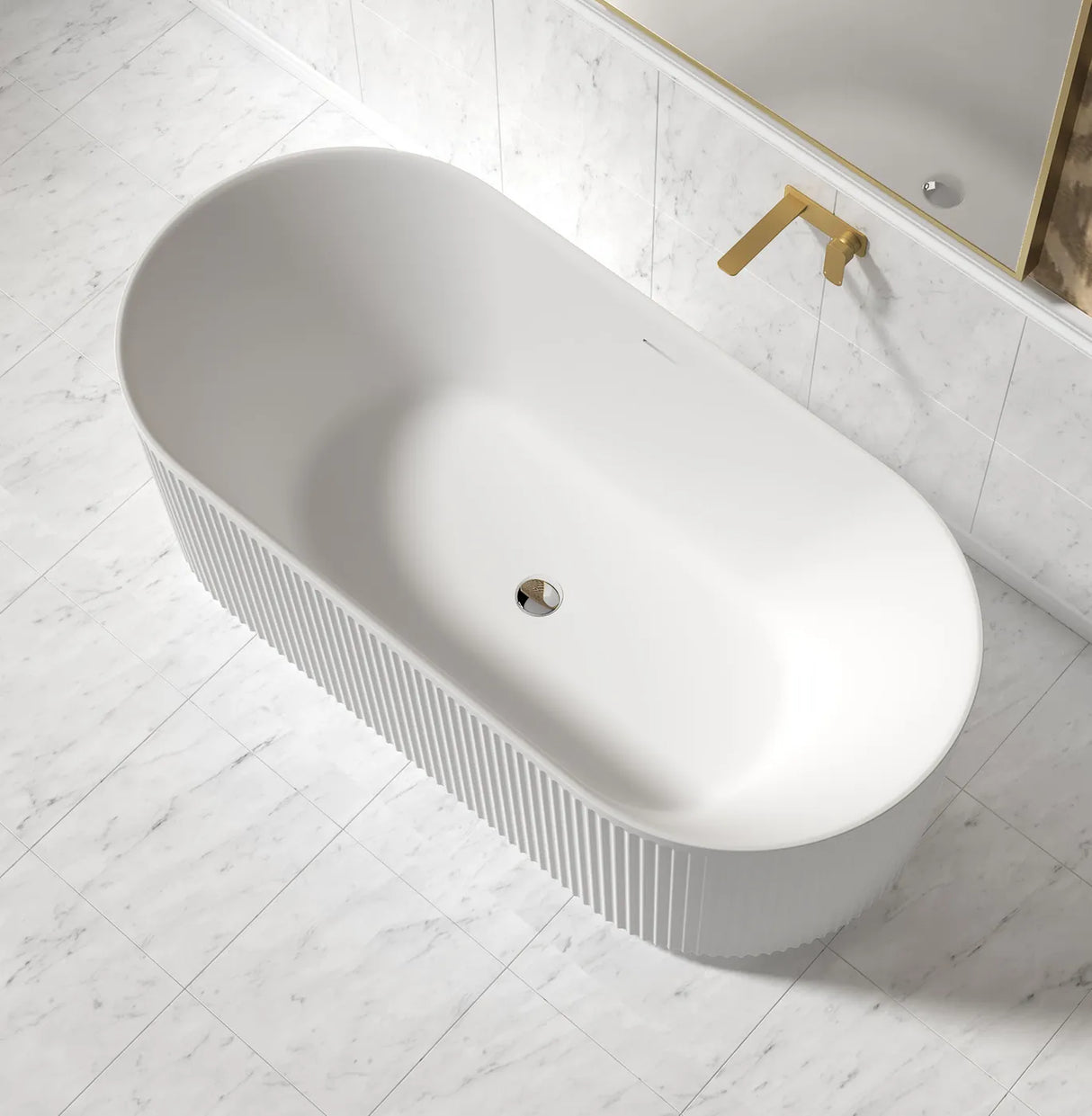 White freestanding bathtub in a modern bathroom with a gold faucet.