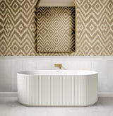 Modern freestanding bathtub in a bathroom with patterned wallpaper and mirror.