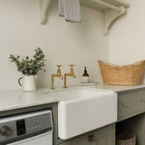 Kitchen with white sink, gold faucets, and various items on the counter.