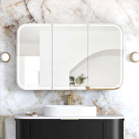Bathroom vanity with black cabinet, white sink, and gold fixtures against a marble wall.